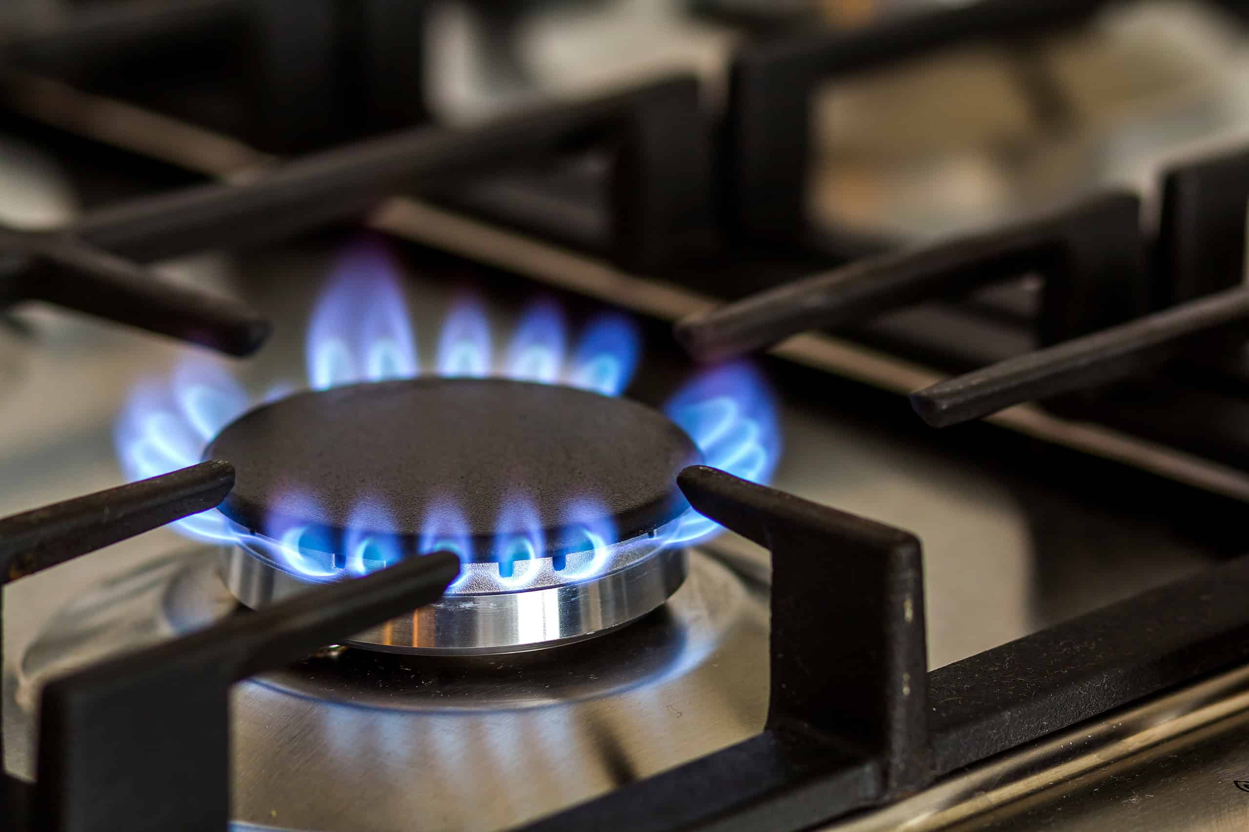 Natural gas burning on kitchen gas stove in the dark. Panel from steel with a gas ring burner on a black background, close-up shooting